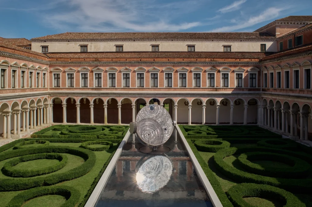 Claustro palladiano da Fondazione Giorgio Cini com jardim de buxos e, no centro, um espelho d'água estreito com um grande disco espelhado que se reflete na água