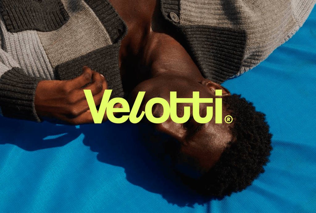 Logotipo Velotti em verde-limão sobre uma pessoa de roupa azul, vista de cima