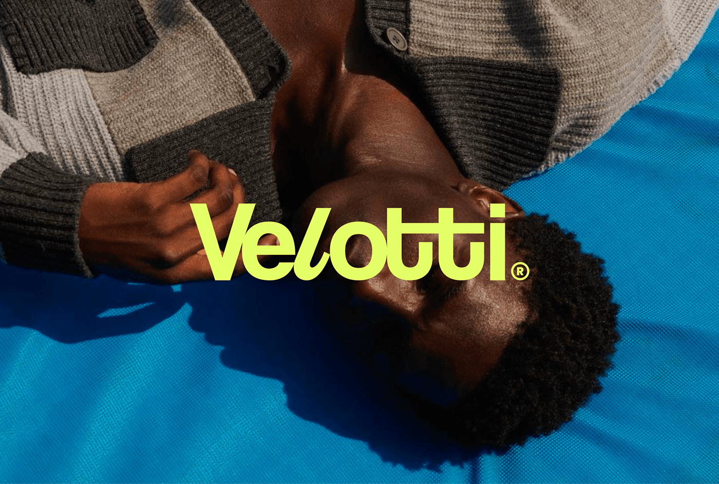 Logotipo Velotti em verde-limão sobre uma pessoa de roupa azul, vista de cima