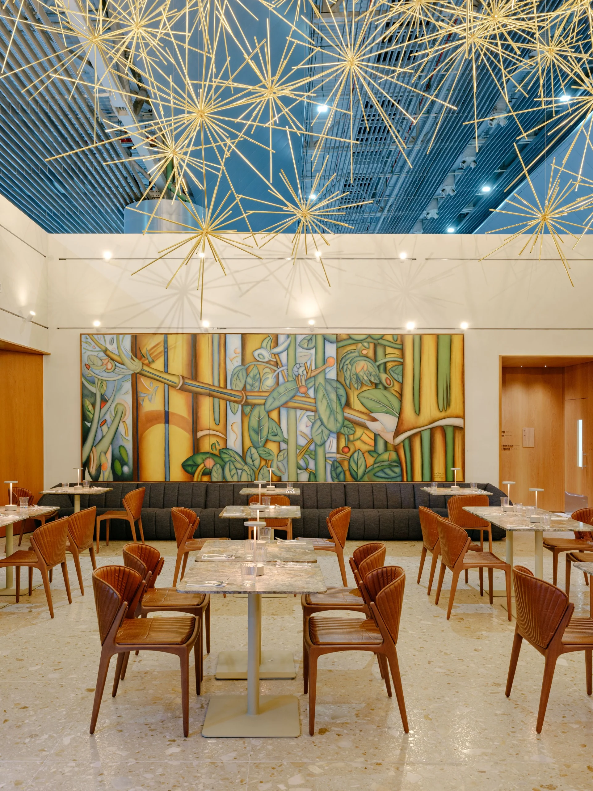 Restaurante Personnalité com a instalação Cosmos, hastes douradas em forma de estrelas suspensas sob o teto do terminal, e uma pintura grande na parede